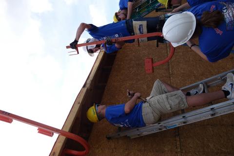 First, we installed roof "guardrails". Each of the J-shaped things support three 2x4's, forming a railing. Setting up roof guards.
