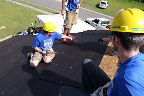 A few people unrolled tarpaper. Then everyone nailed down their little 3' wide swath and we all moved up the roof. Went fast. Laying tar paper